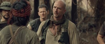 Movie still from “Rambo” (2008), directed by Sylvester Stallone – A man with a beard and a scarf around his neck; Close Up shot, Over the shoulder angle