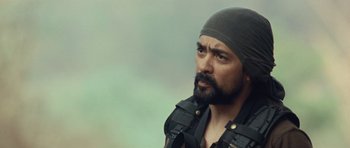 Movie still from “Rambo” (2008), directed by Sylvester Stallone – A man with a beard wearing a black hat; Close Up shot, Over the shoulder angle