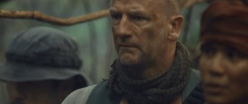 Movie still from “Rambo” (2008), directed by Sylvester Stallone – A bald man with a scarf around his neck; Close Up shot, Low angle