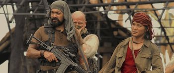 Movie still from “Rambo” (2008), directed by Sylvester Stallone – A group of men standing next to each other holding guns; Medium shot, Over the shoulder angle