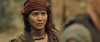 Movie still from “Rambo” (2008), directed by Sylvester Stallone – A man wearing a red hat and a necklace; Close Up shot, Over the shoulder angle