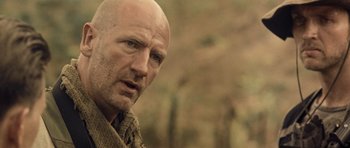 Movie still from “Rambo” (2008), directed by Sylvester Stallone – A man with a bald head wearing a scarf; Close Up shot, Over the shoulder angle