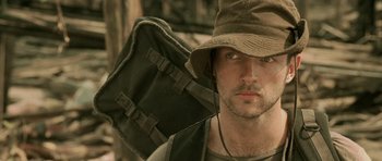Movie still from “Rambo” (2008), directed by Sylvester Stallone – A person wearing a hat and holding a backpack; Close Up shot, Low angle