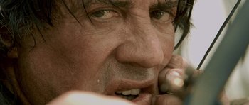 Movie still from “Rambo” (2008), directed by Sylvester Stallone – A man's face while holding a cell phone to his ear; Extreme Close Up shot, Low angle
