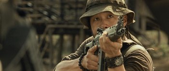Movie still from “Rambo” (2008), directed by Sylvester Stallone – A man holding a rifle while wearing a hat; Close Up shot, Low angle
