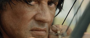 Movie still from “Rambo” (2008), directed by Sylvester Stallone – A man's face while holding a pair of scissors in his hand; Extreme Close Up shot, Low angle