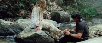 Movie still from “Rambo” (2008), directed by Sylvester Stallone – A woman sitting on a rock next to a man; Wide shot, High angle