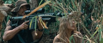 Movie still from “Rambo” (2008), directed by Sylvester Stallone – A woman is holding a rifle in the woods; Medium shot, Over the shoulder angle