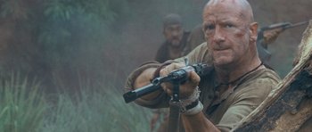 Movie still from “Rambo” (2008), directed by Sylvester Stallone – A man holding a gun while standing next to another man; Close Up shot, Low angle