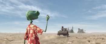 Movie still from “Rango” (2011), directed by Gore Verbinski – A green frog is standing in front of an old car; Wide shot, Over the shoulder angle