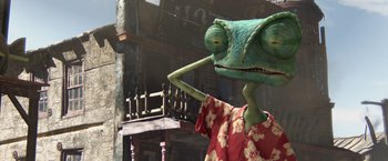 Movie still from “Rango” (2011), directed by Gore Verbinski – A green lizard is standing in front of a building; Extreme Close Up shot, High angle
