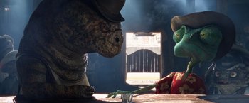 Movie still from “Rango” (2011), directed by Gore Verbinski – A stuffed dinosaur sitting on top of a wooden table; Medium shot, Over the shoulder angle