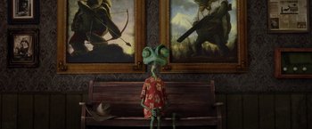 Movie still from “Rango” (2011), directed by Gore Verbinski – A person sitting on top of a wooden bench next to two paintings; Wide shot, High angle