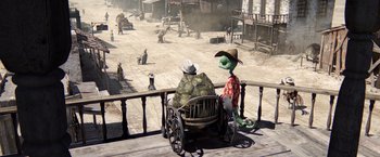 Movie still from “Rango” (2011), directed by Gore Verbinski – A person sitting on a chair next to another person; Wide shot, High angle