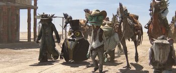 Movie still from “Rango” (2011), directed by Gore Verbinski – A man with a hat and a frog costume on; Wide shot, Low angle