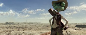 Movie still from “Rango” (2011), directed by Gore Verbinski – An image of an alien holding a book in the desert; Wide shot, Low angle