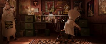 Movie still from “Ratatouille” (2007), directed by Jan Pinkava – A person sitting at a desk in front of a clock; Wide shot, High angle