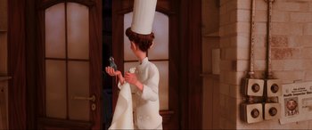 Movie still from “Ratatouille” (2007), directed by Jan Pinkava – An animated character in a chef's outfit holding a cell phone; Medium shot, Over the shoulder angle
