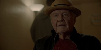 Movie still from “Ray Donovan: The Movie” (2022), directed by David Hollander – An older man wearing a hat and a jacket; Close Up shot, Over the shoulder angle