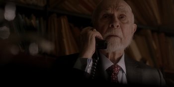 Movie still from “Ray Donovan: The Movie” (2022), directed by David Hollander – An older man talking on a phone while wearing a suit and tie; Close Up shot, High angle