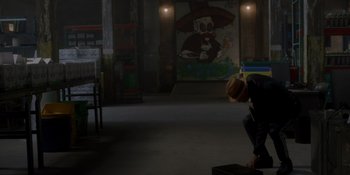 Movie still from “Ray Donovan: The Movie” (2022), directed by David Hollander – A man in a hat is squatting in a dark room; Wide shot, Low angle