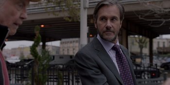 Movie still from “Ray Donovan: The Movie” (2022), directed by David Hollander – A person wearing a suit and tie; Close Up shot, Over the shoulder angle