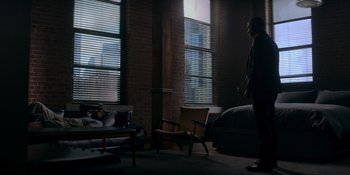 Movie still from “Ray Donovan: The Movie” (2022), directed by David Hollander – A man standing in a room next to a bed; Wide shot, High angle