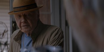 Movie still from “Ray Donovan: The Movie” (2022), directed by David Hollander – An older man wearing a hat and a jacket; Close Up shot, Over the shoulder angle