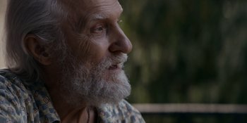 Movie still from “Ray Donovan: The Movie” (2022), directed by David Hollander – An old man with a beard is looking into the distance; Close Up shot, Over the shoulder angle