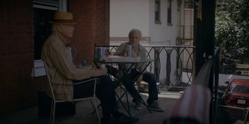 Movie still from “Ray Donovan: The Movie” (2022), directed by David Hollander – Two older men sitting at a table on a porch; Wide shot, Over the shoulder angle