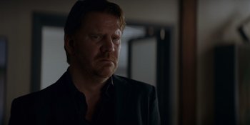 Movie still from “Ray Donovan: The Movie” (2022), directed by David Hollander – A person wearing a suit and tie; Close Up shot, Over the shoulder angle