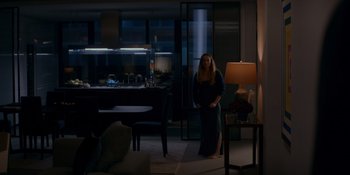 Movie still from “Ray Donovan: The Movie” (2022), directed by David Hollander – A woman standing in a living room in front of a kitchen; Wide shot, High angle