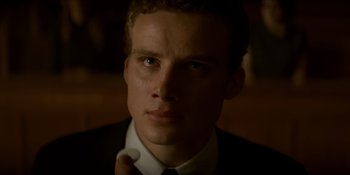 Movie still from “Ray Donovan: The Movie” (2022), directed by David Hollander – A man in a black suit and white tie; Close Up shot, Over the shoulder angle