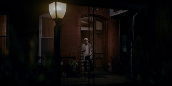 Movie still from “Ray Donovan: The Movie” (2022), directed by David Hollander – An older man standing in front of a door way; Wide shot, High angle
