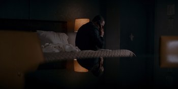 Movie still from “Ray Donovan: The Movie” (2022), directed by David Hollander – A man sitting on a bed talking on the phone; Medium shot, High angle