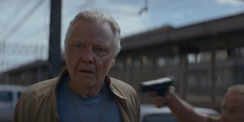 Movie still from “Ray Donovan: The Movie” (2022), directed by David Hollander – An older man holding a gun in front of him; Close Up shot, Over the shoulder angle
