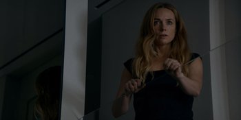 Movie still from “Ray Donovan: The Movie” (2022), directed by David Hollander – A woman holding a pair of scissors in front of a mirror; Close Up shot, Low angle