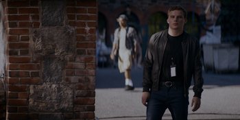 Movie still from “Ray Donovan: The Movie” (2022), directed by David Hollander – A man in a leather jacket is walking down the street; Medium shot, Low angle