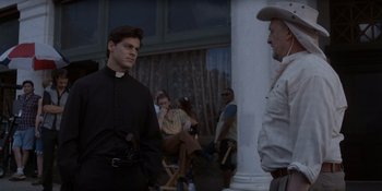 Movie still from “Ray Donovan: The Movie” (2022), directed by David Hollander – A man in a priest's outfit standing next to a man in a cowboy hat; Medium shot, Over the shoulder angle