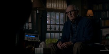 Movie still from “Ray Donovan: The Movie” (2022), directed by David Hollander – An older man sitting in a chair in front of a lamp; Medium shot, Over the shoulder angle