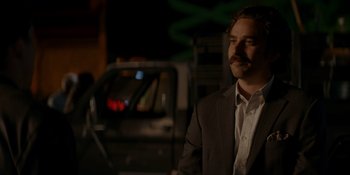 Movie still from “Ray Donovan: The Movie” (2022), directed by David Hollander – A man in a suit standing in front of a car; Close Up shot, Over the shoulder angle