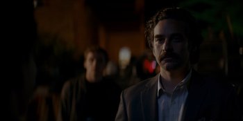 Movie still from “Ray Donovan: The Movie” (2022), directed by David Hollander – A man in a suit and tie standing next to another man in a suit; Close Up shot, Over the shoulder angle