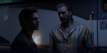 Movie still from “Ray Donovan: The Movie” (2022), directed by David Hollander – Two men standing next to each other in front of a wall; Medium shot, Over the shoulder angle