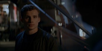 Movie still from “Ray Donovan: The Movie” (2022), directed by David Hollander – A young man is standing in a dark room; Close Up shot, Low angle