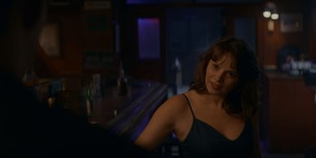 Movie still from “Ray Donovan: The Movie” (2022), directed by David Hollander – A woman sitting at a bar with a bottle of beer; Medium shot, Over the shoulder angle