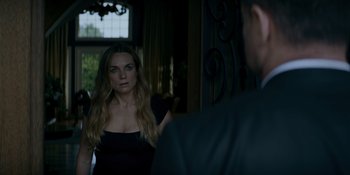 Movie still from “Ray Donovan: The Movie” (2022), directed by David Hollander – A woman standing in front of a man in front of a mirror; Medium shot, Over the shoulder angle