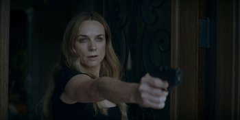 Movie still from “Ray Donovan: The Movie” (2022), directed by David Hollander – A woman holding a gun in a dark room; Close Up shot, Over the shoulder angle