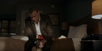 Movie still from “Ray Donovan: The Movie” (2022), directed by David Hollander – A man sitting on a bed with a knife in his hand; Medium shot, Low angle