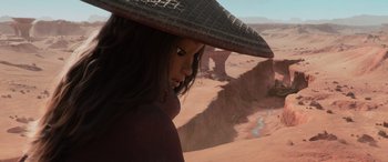 Movie still from “Raya and the Last Dragon” (2021), directed by Don Hall – A woman with a hat is standing in the desert; Close Up shot, Over the shoulder angle