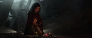 Movie still from “Raya and the Last Dragon” (2021), directed by Don Hall – A woman lighting candles on top of a table; Medium shot, Over the shoulder angle